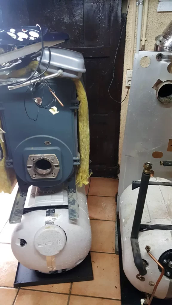 Depósito acumulador junto a caldera antigua en sala técnica.