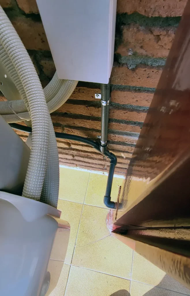 Tuberías y conexiones tras la instalación de aire acondicionado en pared de ladrillo.
