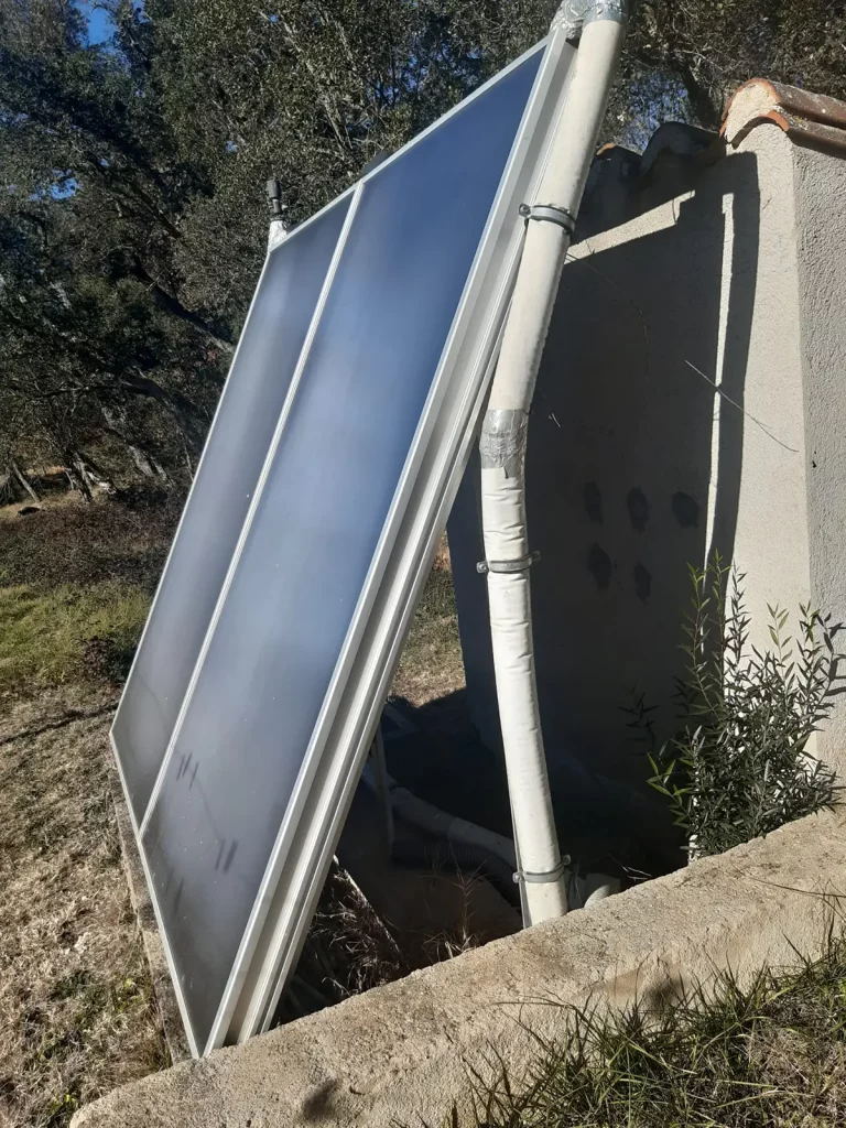 Panel solar térmico montado en estructura metálica orientada hacia el sol en entorno rural.